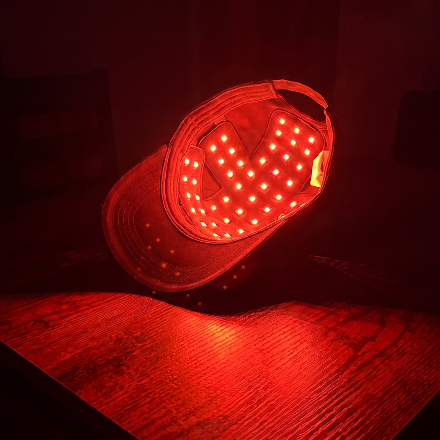 Optimal red light therapy cap glowing on a table